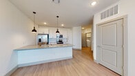 This well-designed single-floor residence offers a clean, contemporary aesthetic throughout, highlighted by light wood-style flooring and crisp white walls that create a bright and welcoming atmosphere. The heart of the home is a thoughtfully designed open-concept kitchen featuring a large central island topped with granite countertops and an undermount sink with a professional-style faucet. Sleek white shaker cabinetry with modern hardware lines the walls, complemented by a full suite of stainless steel appliances, including a French door refrigerator, electric range, over-the-range microwave, and dishwasher. Pendant lighting above the island adds a stylish focal point. The kitchen flows seamlessly into the living area, which benefits from natural light streaming through large windows fitted with blinds. The bedroom is a serene retreat, carpeted for comfort, and features dual windows that invite ample natural light and outdoor views. The bathroom is finished with matching granite countertops, white cabinetry, an undermount sink, and a tiled tub-shower combination. A dedicated in-unit laundry closet with a stacked washer and dryer adds practical convenience, completing this move-in-ready residence.