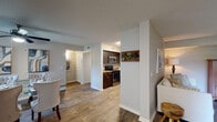 This single-floor residence offers a cohesive and functional layout highlighted by wood-look flooring that runs continuously throughout the space, lending warmth and visual consistency to every room. The kitchen is well-equipped with dark espresso cabinetry, granite-style countertops, and a full suite of stainless steel appliances, including a refrigerator, dishwasher, microwave, and gas range. An open corridor connects the kitchen to the main living and dining areas. The dining room features a ceiling fan and natural light from a window, creating a pleasant setting for meals. The living room provides a relaxed, comfortable atmosphere with warm ambient lighting. A versatile flex room, brightened by a window with outdoor views, is well-suited as a home office or sitting area. The primary bathroom is notably spacious, offering dual vanities with dark-framed mirrors, mirrored sliding closet doors, wood-look flooring, and a separate toilet and shower area. A secondary bathroom includes a tub-shower combination and a single vanity. Bedrooms feature mirrored sliding closet doors and natural light. A dedicated laundry room houses full-sized washer and dryer units, adding practical convenience to the overall layout.