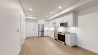 Located in Redmond, WA, this thoughtfully designed one-bedroom, one-bathroom unit delivers a clean, contemporary aesthetic throughout its efficiently arranged single-floor layout. The open-concept kitchen and living area serves as the heart of the home, showcasing white flat-panel cabinetry extending to the ceiling, a marble-style tile backsplash, light wood-look flooring, and a full suite of stainless steel appliances including a French door refrigerator, electric range, built-in microwave, and dishwasher. Recessed lighting illuminates the kitchen, adding a polished, modern finish. The living area flows seamlessly from the kitchen, offering a bright, open canvas framed by light-toned walls and consistent flooring throughout. The bedroom is a comfortable, well-proportioned retreat featuring large floor-to-ceiling windows that frame verdant outdoor greenery, filling the space with natural light and a sense of connection to nature. Dark wood-look flooring anchors the room with warmth. The bathroom is finished with marble-style large-format wall tile in the tub-shower surround, light wood flooring, and clean white cabinetry. A connecting hallway provides practical flow between rooms. The overall ambiance is modern, clean, and move-in ready.