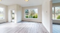 Located along Island Highway North in Nanaimo, BC, this well-appointed 2-bedroom, 2-bathroom unit offers a clean, contemporary design across a single-level floor plan. Light-toned luxury vinyl plank flooring runs throughout, complementing the bright, neutral palette that defines each room.

The modern kitchen is a standout feature, showcasing high-gloss white cabinetry, a classic white subway tile backsplash, quartz-style countertops, and stainless steel appliances including a range and full-size refrigerator. A central island provides additional prep and dining space, while recessed lighting overhead adds a polished finish. The kitchen opens toward the living area, which benefits from large windows framing views of the surrounding greenery.

Both bedrooms are comfortably sized with generous windows that invite natural light and offer peaceful outdoor views. The primary bedroom provides a quiet retreat with its own dedicated closet. The two bathrooms are finished in a consistent modern style — one featuring a soaker tub and shower combination, the other with a floating vanity, undermount sink, and large mirror. Baseboard heating is present throughout. The overall ambiance is clean, bright, and move-in ready.