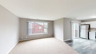 Located at 1157 S Wells St in Lake Geneva, Wisconsin, this 2-bedroom, 1-bathroom single-floor unit offers a well-designed layout with functional and modern finishes throughout. The living area is bright and inviting, featuring plush neutral carpeting, soft gray walls, and a large picture window that fills the space with natural light and provides views of the surrounding neighborhood. A sliding glass door adds additional light and leads to an outdoor deck, extending the living space outdoors. The kitchen is a standout feature, outfitted with crisp white shaker-style cabinetry, light countertops, and a full suite of stainless steel appliances including a refrigerator, range, microwave, and dishwasher. Light wood-tone flooring completes the clean, contemporary look. Both bedrooms are carpeted with neutral tones and feature ample closet space with built-in shelving, including a generously sized primary bedroom. The bathroom is finished with a dark vanity cabinet topped with a white countertop, a large mirror, and stylish light fixtures, complemented by the same wood-tone flooring found in the kitchen. Clean lines and a consistent neutral palette create a cohesive and comfortable atmosphere throughout this Lake Geneva residence.