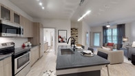 Located at 13645 E Colonial Dr in Orlando, Florida, this single-floor residence offers a thoughtfully designed contemporary living space with modern finishes throughout. The open-concept kitchen serves as the heart of the home, featuring warm wood-toned cabinetry, dark granite countertops, a subway tile backsplash, stainless steel appliances, and a large central island with seating — ideal for both cooking and casual dining. Light wood-style flooring flows seamlessly throughout the main living areas, complementing the bright, neutral color palette. The living room is generously proportioned, bathed in natural light from large windows dressed with floor-to-ceiling drapes, and offers direct access to an outdoor area through a glass-paneled door. The bedrooms are comfortable and well-sized, each featuring plush carpeting, ceiling fans, and large windows that allow ample natural light. The primary bathroom is a standout, offering an extended dual-sink vanity with granite countertops, wood cabinetry, a walk-in glass shower with white subway tile, and light wood flooring. Throughout the space, the design balances modern aesthetics with practical functionality, creating a cohesive and inviting atmosphere ideal for contemporary living in Orlando.