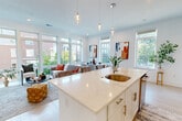 Located at 95 Fawcett St in Cambridge, MA, this thoughtfully designed 3-bedroom, 2-bathroom residence offers a bright, open-concept layout across a single floor. The heart of the home is a seamlessly connected kitchen, dining, and living area flooded with natural light from expansive floor-to-ceiling windows. The chef's kitchen is anchored by a striking quartz waterfall island with a brass undermount sink, complemented by white shaker cabinetry with gold hardware, subway tile backsplash, and a full suite of stainless steel appliances. Pendant lighting adds a refined touch overhead. The living area offers generous proportions and direct views of the surrounding neighborhood through large glazed panels. The dining space features clean white walls adorned with bold abstract artwork and windows that invite in ample daylight. The spacious primary bedroom includes a double-door closet and serene, neutral tones. Secondary bedrooms are well-sized with natural light and a calm, minimal aesthetic. Both bathrooms are finished in crisp white with quartz vanities; one features a large frameless glass walk-in shower with marble-style tile. Light wood flooring flows throughout, tying the home together with warmth and cohesion.