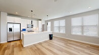 This well-appointed single-story home offers a thoughtful layout across three bedrooms, two bathrooms, and a dedicated laundry room. The open-concept kitchen and living area serves as the heart of the home, featuring light hardwood flooring, recessed lighting, and an abundance of natural light from multiple windows dressed with white blinds. The kitchen is outfitted with crisp white shaker cabinetry, a white subway tile backsplash, stainless steel appliances including a side-by-side refrigerator, built-in microwave, and range, all centered around a peninsula with a undermount sink — ideal for both cooking and casual dining. The adjacent living area is bright and open, with pendant lighting adding a modern touch. The bedrooms offer plush carpeting, ceiling fans, and windows that bring in natural light. The primary bedroom is a comfortable retreat with ample space. Both bathrooms are finished with clean white cabinetry and quartz countertops; one features a full tub-shower combo clad in classic white subway tile. The dedicated laundry room includes a full-size washer and dryer. Neutral gray walls and white trim carry a cohesive, contemporary aesthetic throughout the entire home.