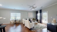 Located at 1004 Bailes Ridge Ave in Fort Mill, SC, this 2-bedroom, 1-bathroom residence offers a thoughtfully designed single-floor layout with a cohesive, modern aesthetic. The open-concept living and dining area is anchored by rich hardwood-style flooring, crown molding, and soft sage-green walls that lend a calm, inviting atmosphere. A ceiling fan and multiple windows allow for generous natural light, while a sliding door provides outdoor access directly from the living space. The kitchen is well-equipped with dark espresso cabinetry, granite countertops, a tile backsplash, and stainless steel appliances, offering both style and functionality. A versatile flex space adjacent to the dining area can serve as a home office or additional dining room. The primary bedroom features plush carpet, a teal accent wall, a ceiling fan, and wide windows that bring in ample natural light, complemented by a spacious walk-in closet with built-in shelving. The second bedroom is equally comfortable with neutral tones and bright windows. The full bathroom includes dark vanity cabinetry, a white countertop, and tile flooring, providing a clean and polished finish. Throughout the residence, consistent attention to detail and quality finishes create a welcoming and functional living environment.