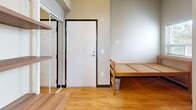 Located at 4743 21st Ave NE in Seattle's vibrant University District, this efficiently designed one-bedroom, one-bathroom unit offers a thoughtful layout that maximizes every inch of its compact footprint. Warm-toned hardwood floors run throughout the space, lending a clean and inviting aesthetic that ties the rooms together cohesively.

The main living and sleeping area features notably tall ceilings that create an airy, open feel despite the intimate scale of the unit. Multiple windows admit generous natural light, brightening the neutral-toned walls and enhancing the sense of openness. A built-in kitchenette is neatly tucked along one wall, outfitted with white cabinetry, a microwave, and a compact refrigerator — providing all essential amenities in a streamlined footprint.

Built-in wall shelving and a fold-down desk offer practical, space-efficient storage and workspace solutions within the bedroom area. A sliding glass-panel closet door provides access to dedicated wardrobe storage without intruding on the living space.

The private bathroom features a white vanity with under-cabinet storage, an overhead medicine cabinet, and a shower, all finished in a clean, functional style. The overall ambiance of the unit is bright, minimal, and well-organized — well-suited for those seeking a practical and comfortable residence in one of Seattle's most walkable neighborhoods.
