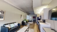 Located at 318 Park Central E in the heart of Springfield, Missouri, Unit 302 is a thoughtfully designed urban residence that blends industrial character with modern comfort. The open-concept living and dining area serves as the centerpiece of the unit, showcasing striking exposed concrete ceilings, wood-look flooring, and generous wall height that lend a loft-like atmosphere. Natural light filters in through large windows, enhancing the airy feel of the main living space.

The kitchen is outfitted with gray cabinetry, white quartz-style countertops, and a full suite of stainless steel appliances including a refrigerator, electric range, over-the-range microwave, and dishwasher — providing both function and a clean, contemporary aesthetic.

The unit features multiple bedrooms, each offering a quiet and comfortable retreat with neutral tones and wood-look flooring. The bathrooms are finished with modern gray vanities, white countertops, large mirrors, and wood-look tile flooring, with one bathroom featuring a walk-in shower.

A hallway adorned with framed artwork connects the private quarters to the main living areas, adding a welcoming touch. Dark-framed doors and trim provide stylish contrast throughout, contributing to the unit's cohesive urban-modern design.