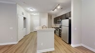 Located at 112 29th Avenue Dr NW in Hickory, NC, this single-floor, 2-bedroom, 2-bathroom residence offers a thoughtfully designed layout with a clean, neutral aesthetic throughout. The open-concept kitchen and living area serves as the heart of the home, featuring a peninsula with a sink, rich dark-brown cabinetry, light countertops, and a full suite of stainless steel appliances including a range, microwave, and refrigerator. Track lighting and hardwood-style flooring complete the kitchen's polished look. The living room is bright and airy, highlighted by crown molding, a ceiling fan, and French doors that open to an outdoor space, allowing natural light to pour in. A dedicated in-unit laundry area adds everyday convenience. The two bedrooms are carpeted for comfort, each offering natural light through well-positioned windows. The primary bedroom includes a ceiling fan and direct access to one of the two bathrooms. Both bathrooms are consistently styled with dark vanity cabinetry, light countertops, large mirrors, and hardwood-style flooring. One bathroom features a full tub-shower combination. A connecting hallway ties the layout together efficiently, making this a functional and inviting residence.