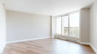 Located at 1071 Ambleside Dr in Ottawa's K2B neighbourhood, this 2-bedroom, 1-bathroom unit offers a clean, modern aesthetic throughout its efficiently designed single-floor layout. Light-toned hardwood flooring runs continuously throughout the space, lending a warm, cohesive feel to every room.

The living room is a standout feature, anchored by large sliding windows and balcony access that flood the space with natural light and offer open views of the surrounding neighbourhood. Baseboard heating units line the walls beneath the windows, ensuring year-round comfort.

The kitchen is well-equipped with white shaker-style cabinetry, a classic subway tile backsplash, dark countertops, and a full suite of stainless steel appliances, including a range, dishwasher, and refrigerator.

Both bedrooms are bright and functional. The primary bedroom is a comfortable size and features a built-in double closet, while the second bedroom includes a window with natural light and its own baseboard heating. A central hallway with an additional closet connects the rooms efficiently.

The bathroom is finished with large-format neutral tile surrounding a full soaking tub and shower combination, complemented by chrome fixtures. The overall palette of warm neutrals and white trim gives the entire unit a fresh, move-in-ready appearance.