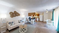 Located at 1040 Ocean Pebbles Way in Virginia Beach, VA, this thoughtfully designed single-floor residence offers a comfortable and functional layout with a distinct coastal aesthetic. The open-concept living and dining area features warm wood-look flooring, crisp white walls, and beach-inspired décor — including woven wall art and teal accents — creating a relaxed, welcoming atmosphere. The space flows seamlessly into a well-appointed kitchen equipped with warm wood cabinetry, granite-look countertops, and a full suite of white appliances, including a range, microwave, dishwasher, and refrigerator. A dedicated office provides a carpeted, windowed workspace ideal for productivity, complete with natural light and ample room for furnishings. The generously sized primary bedroom features plush carpeting, sliding glass door access to an outdoor area, and large teal-draped windows that fill the room with natural light. Two bathrooms serve the residence, one featuring a sleek glass-enclosed shower. Additional highlights include a closet for storage and a well-defined hallway connecting each room. The overall ambiance is bright, airy, and cohesive — reflecting the relaxed charm of its Virginia Beach location.
