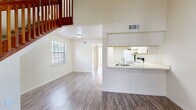 This two-story residence offers a well-organized layout that balances open communal spaces with comfortable private retreats. The main level centers on a bright, open-concept living area finished with durable wood-style flooring and soaring ceilings that lend a generous sense of height and airiness. Natural light filters in through multiple windows, keeping the space feeling fresh and inviting. A pass-through kitchen counter seamlessly connects the kitchen to the living area, making the floor plan ideal for everyday functionality. The kitchen itself is well-equipped with white cabinetry, a refrigerator, electric range, dishwasher, and ample counter space. A richly toned wood-railed staircase leads to the upper level, where the bedrooms are located. Each bedroom features ceiling fans, neutral carpeting or wood-style flooring, and windows that allow natural light to brighten the rooms. The bathrooms are clean and functional, each equipped with a full tub-shower combo and efficient fixtures. Throughout the home, a neutral color palette of soft whites and warm beiges creates a cohesive, calming atmosphere. The consistent use of wood-style flooring across much of the main level ties the space together for a polished, uniform look.