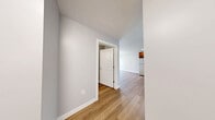 This well-designed one-bedroom, one-bathroom unit in Manchester, NH offers a thoughtfully organized layout across a single floor. The kitchen serves as a functional centerpiece, outfitted with rich warm-toned wood cabinetry, light gray countertops, and a full suite of stainless steel appliances including a refrigerator, range, microwave, and dishwasher. Recessed lighting illuminates the space, which is grounded by light hardwood-style flooring that extends throughout the main living areas, creating a cohesive and inviting atmosphere.

The bedroom offers a comfortable and private retreat, featuring plush neutral carpeting and a large window that brings in natural light while providing views of the surrounding cityscape. The soft gray walls throughout the unit lend a clean, modern aesthetic that complements the overall design.

The bathroom maintains the same contemporary style, with a warm wood vanity, gray stone-style countertop, a large mirror with overhead lighting, and consistent hardwood-style flooring. The space is clean and efficiently arranged.

An entrance area provides a practical transition into the unit. Overall, this residence combines modern finishes, functional design, and a neutral color palette to create a comfortable and stylish living environment in the heart of Manchester, NH.