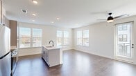 Located at 103 East 2nd Street in Richmond, VA, this well-appointed 2-bedroom, 2-bathroom residence offers a thoughtfully designed single-level layout with modern finishes throughout. The open-concept living and kitchen area forms the heart of the home, anchored by a central island with a sleek black faucet and white countertop that doubles as a prep and gathering space. The kitchen features gray shaker-style cabinetry, stainless steel appliances including a refrigerator, electric range, and built-in microwave, all set against light hardwood-style flooring. The living area is generously proportioned, bathed in natural light from multiple windows, and equipped with a ceiling fan. The primary bedroom offers comfortable carpeting, a ceiling fan, and a dedicated closet, while the second bedroom provides hardwood-style flooring and ample natural light through large windows. Both bathrooms are finished with white vanities, black hardware accents, and wood-style flooring for a clean, contemporary aesthetic. Two closets provide practical storage throughout the home. The overall design is clean and modern, with a neutral color palette, recessed lighting, and consistent attention to detail that gives the space a bright, welcoming ambiance.