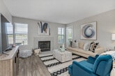 This single-story, 2-bedroom, 3-bathroom residence offers a thoughtfully organized layout that balances comfort and functionality throughout. The living room serves as the heart of the home, featuring a tile-surround fireplace flanked by multiple windows that invite abundant natural light. Wood-style flooring runs through the main living areas, complementing the neutral color palette that gives the space a clean, cohesive aesthetic.

The galley-style kitchen is efficiently appointed with white shaker cabinetry, light countertops, a gray tile backsplash, and a full suite of stainless steel appliances, including a range, microwave, refrigerator, and dishwasher. A closeted pantry provides additional storage. Adjacent to the kitchen, the dining area accommodates a full-sized table beneath a pendant light fixture, with rustic floating shelves adding decorative character to the walls.

Both bedrooms feature plush carpeting and ample closet space. The primary bedroom is a comfortable retreat with a ceiling fan and a window overlooking greenery. The second bedroom also provides generous room and a large sliding closet. Three bathrooms serve the home, each finished with wood-look tile flooring and clean, understated fixtures. Throughout, textured ceilings and neutral wall tones create a calm, inviting atmosphere well-suited for everyday living.