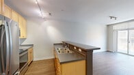 Located in the heart of downtown Milwaukee at 144 N Jefferson St, this one-bedroom, one-bathroom residence offers a well-designed single-floor layout. Warm hardwood-style flooring flows throughout, creating a cohesive and inviting aesthetic across all rooms.

The kitchen is a functional standout, featuring light maple cabinetry, dark laminate countertops, stainless steel appliances — including a large French door refrigerator, range, and built-in microwave — and a peninsula with an extended breakfast bar that opens to the living area. Track lighting overhead provides ample task illumination.

The living room is bright and open, anchored by a full-height sliding glass door that leads to a private balcony overlooking the surrounding urban streetscape, allowing natural light to fill the space throughout the day.

The bedroom is comfortably sized, finished with the same flooring, neutral walls, and a large window that reinforces the airy feel. A dedicated closet provides practical storage, and the bedroom connects conveniently to the full bathroom.

The bathroom is cleanly appointed with a single-sink vanity featuring maple cabinetry, a large mirror with Hollywood-style lighting, a tiled tub-shower combination, and matching hardwood-style flooring that ties the space together seamlessly.
