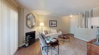 This single-story residence is thoughtfully laid out to maximize comfort and functionality across its key living spaces. The living room serves as the central gathering area, anchored by a wood-burning fireplace framed by white paneling and accented with crown molding. Textured ceilings carry throughout the home, lending a consistent architectural character. Hard surface flooring runs through the main living and dining areas, while plush carpet adds warmth to the bedrooms.

The living room flows naturally into a separate dining area, which benefits from a ceiling fan and windows that invite natural light. A sliding glass door in the living space connects to the outdoors. The galley-style kitchen features wood cabinetry, a double basin sink, electric range, dishwasher, and hardwood-style flooring, with efficient use of the available space.

Both bedrooms are carpeted and comfortably sized, each with closet access. One bedroom includes a window that brings in additional natural light. The bathroom offers a wide vanity with oak cabinetry, a large mirror, and a multi-bulb light fixture above the sink. Overall, the home presents a warm, neutral palette that creates a cohesive and inviting atmosphere.