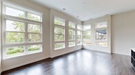 Located at 101 Washington St in Conshohocken, PA, this well-appointed 2-bedroom, 2-bathroom residence offers a thoughtfully designed single-floor layout with generous living space. The open-concept kitchen and living area is a standout, featuring soaring ceilings, rich hardwood flooring, and floor-to-ceiling windows that flood the space with natural light and offer views of lush greenery. The contemporary kitchen is outfitted with two-tone cabinetry in white gloss and dark wood grain, stainless steel appliances including a built-in oven, dishwasher, and French door refrigerator, complemented by a sleek center island with a white quartz countertop and integrated shelving. The living room continues the open, airy feel with expansive corner windows framing scenic outdoor views. Both bedrooms are carpeted and generously sized, with the primary bedroom boasting high ceilings and direct access to an en-suite bathroom featuring a glass-enclosed marble-tiled shower, a floating dark wood vanity, and an illuminated mirror. The second bathroom includes a soaking tub with marble tile surround and matching modern finishes. Two closets provide ample storage, and a private outdoor patio with landscaped plantings completes this refined residence.