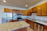 Located at 1100 Hunters Run Dr in Grand Blanc, Michigan, this single-story home offers a thoughtfully designed layout across two bedrooms, two bathrooms, and multiple closets. The entryway makes a strong first impression with elegant wainscoting panels, warm hardwood-style flooring, recessed lighting, and a bold dark front door flanked by a large window that invites natural light into the space.

The open-concept living and kitchen area forms the heart of the home. The kitchen is outfitted with rich warm-toned cabinetry, granite countertops, a central island, stainless steel appliances including a refrigerator, range, microwave, and dishwasher, and a double undermount sink — combining both style and functionality.

The bedrooms are bright and comfortable, featuring hardwood-style flooring, recessed lighting, and windows providing natural light. The spacious primary bedroom includes generous walk-in closet space with wire shelving. The bathrooms are finished with large-format tile surrounds in the tub/shower areas.

A dedicated laundry room houses a full-size washer and dryer along with a water heater. The attached garage provides convenient parking and additional storage. The home's neutral color palette and consistent flooring throughout create a cohesive, move-in-ready feel.