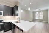 Located at 3838 N Braeswood Blvd in Houston, TX, this one-bedroom, one-bathroom residence offers a thoughtfully designed single-floor layout with modern finishes throughout. Light wood-tone flooring flows seamlessly across the main living areas, complemented by crown molding and neutral warm-gray walls that create a clean, cohesive aesthetic.

The kitchen is a standout feature, showcasing rich dark espresso cabinetry, crisp white quartz countertops, a subway tile backsplash, and a full suite of stainless steel appliances. A peninsula with pendant lighting connects the kitchen to the open-concept dining and living area, which benefits from natural light through elegant arched windows and is equipped with a ceiling fan.

The bedroom is a comfortable retreat, featuring the same arched window design that fills the room with natural light, crown molding, and a ceiling fan. Double doors open to a walk-in closet outfitted with multi-level wire shelving, providing ample organized storage. An additional closet offers further flexibility.

The bathroom includes tile flooring, a tub with subway tile surround, dark cabinetry with white countertops, and louvered closet doors. A dedicated laundry area and utility room add everyday convenience, rounding out a well-organized and functional floor plan.