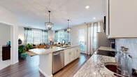Located at 5060 Warner Rd in Westerville, Ohio, this single-floor residence offers a thoughtfully designed open-concept layout with modern finishes and abundant natural light throughout. A welcoming entryway hall leads into the heart of the home, where the kitchen and living spaces flow seamlessly together.

The kitchen is a standout feature, showcasing white shaker cabinetry, granite countertops, a decorative patterned tile backsplash, and a full suite of stainless steel appliances. A central island with seating provides both additional prep space and a casual dining option, while geometric pendant lanterns add a contemporary touch. Large windows and a glass door bathe the area in natural light.

The open living area extends from the kitchen, featuring warm hardwood-style flooring, generous window arrangements, and an inviting atmosphere suited for both relaxing and entertaining. Multiple bedrooms are finished with plush carpeting and windows that bring in soft, natural light. The bathrooms are appointed with granite-topped vanities, white cabinetry, black hardware accents, and a subway tile walk-in shower in the primary bath. A secondary half bath offers granite countertops and hardwood-style flooring. Throughout the residence, cohesive neutral tones and quality finishes create a polished, comfortable living environment.