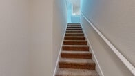 Located at 2785 Chaddsford Circle in Oviedo, FL, this 2-bedroom, 2-bathroom home offers a thoughtfully laid-out single-floor living space with a staircase providing access to additional levels. The open kitchen is well-appointed with white shaker-style cabinetry, light countertops, a stainless steel sink, and black appliances including a range, microwave, dishwasher, and refrigerator, all set on durable wood-look flooring. The combined kitchen and living area creates a functional, open flow throughout the main living space. Both bedrooms feature plush carpeting, and the primary bedroom stands out with vaulted ceilings, a ceiling fan, and a large window that invites natural light and outdoor views. The second bedroom is bright and carpeted as well, with a window fitted with blinds. Each bathroom includes a single vanity with a framed mirror, a tub-shower combination, and wood-look flooring. Both bedrooms are served by walk-in closets with wire shelving systems for organized storage. A dedicated laundry room houses a full-sized washer and dryer. The neutral color palette and clean finishes throughout give the home a bright, move-in-ready feel.