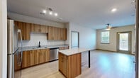 Located at 1000 Chatham Center Drive in Savannah, Georgia, this 2-bedroom, 2-bathroom unit offers a thoughtfully designed single-floor layout with modern finishes throughout. The open-concept kitchen and living area serves as the heart of the unit, where light wood-tone cabinetry, granite countertops, and a full suite of stainless steel appliances—including a refrigerator, range, microwave, and dishwasher—create a functional and contemporary cooking space. A central kitchen island with a matching granite top and sleek black legs provides additional workspace and casual seating. Light hardwood-style flooring extends throughout the main living areas, enhancing the bright, airy feel. The living room benefits from natural light via a window with views of outdoor greenery.

The spacious primary bedroom features direct outdoor access through a glass-panel door alongside a window, and connects to a private bathroom with a wood-grain vanity, granite countertop, and an adjoining walk-in closet with wire shelving. The second bedroom offers plush carpeting, natural light, and a ceiling fan. A second full bathroom mirrors the same refined vanity design. The unit's neutral palette and clean architectural lines contribute to a cohesive, modern ambiance throughout.