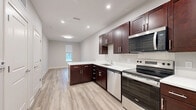 Located at 340 E Fulton St in Columbus, Ohio, this thoughtfully designed one-bedroom, one-bathroom residence offers a clean, contemporary living experience on a single floor. Light-toned luxury vinyl plank flooring runs throughout, complementing the neutral gray walls and white trim to create a bright, cohesive aesthetic.

The open-concept kitchen and living area serves as the heart of the home, featuring rich dark mahogany cabinetry with sleek bar-pull hardware, crisp white countertops, and a full suite of stainless steel appliances including an electric range, built-in microwave, dishwasher, and refrigerator. Recessed lighting illuminates the space, while a peninsula with countertop overhang adds functionality and defines the transition to the living area.

The bedroom is a comfortable, well-proportioned retreat with large windows that invite natural light and provide outdoor views of the surrounding neighborhood. Two closets offer ample storage throughout the unit.

The bathroom is finished in a clean, modern style with a walk-in shower, dark vanity cabinetry with a white countertop, and wood-look tile flooring. A stacked washer and dryer is conveniently located within the bathroom, adding in-unit laundry. A utility room rounds out the layout, providing additional functionality in this efficiently designed urban residence.