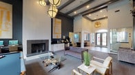 Located at 4795 Franzee in Oceanside, this single-story clubhouse delivers a polished, modern coastal experience from the moment you enter. The main lounge commands attention with soaring ceilings accented by exposed dark beams, dramatic statement pendant lighting, and a bold dark feature wall adorned with sculptural fish artwork — a nod to the coastal surroundings. A floor-to-ceiling fireplace anchors one end of the lounge, while a built-in wet bar with white cabinetry provides a convenient amenity nearby. Comfortable seating arrangements, including a tufted velvet sofa, gold-accented chairs, and glass-topped coffee tables, create an inviting social atmosphere. Large arched windows and glass double doors flood the space with natural light and offer views of the outdoor grounds. A billiards table is positioned beneath a cluster of elegant lantern-style pendants, adding a recreational focal point. A glass-walled leasing office provides transparency and accessibility, while a dedicated conference room features a large communal table, ceiling-mounted projector, and botanical wall art — ideal for meetings or private gatherings. Throughout, the design balances sophisticated finishes with approachable comfort, making this clubhouse a standout community amenity.