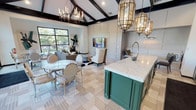 Located at 3501 W Walnut Hill Ln in Irving, Texas, this elegantly appointed single-floor clubhouse offers a sophisticated blend of design and functionality. The open-concept main gathering area is anchored by soaring vaulted ceilings with striking dark wood beam detailing, creating a dramatic architectural backdrop. Ornate antique-gold lantern pendants and a candelabra-style chandelier cast warm ambient light throughout the space, complementing the refined parquet-patterned tile flooring below.

A standout kitchen bar island features bold hunter green cabinetry paired with a sweeping white quartz countertop with grey veining, flanked by matching green upper cabinets and a dramatic dark marble backsplash. The lounge area offers comfortable seating with large black-framed windows that frame lush greenery and pool views, flooding the space with natural light.

Glass-walled partitions separate a dedicated co-working area and fitness room, maintaining an open and airy atmosphere while providing distinct functional zones. Full-length glass doors open directly onto an outdoor patio equipped with lounge seating and string lighting, seamlessly connecting the interior to the exterior. The overall ambiance is upscale and contemporary, with curated artwork and metallic accents enhancing the space's polished, resort-inspired character.