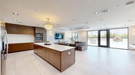 Located in Bixby, Oklahoma, this contemporary single-floor space offers a thoughtfully designed open-concept layout finished with a clean, modern aesthetic throughout. Large-format white tile flooring flows seamlessly across the main living and kitchen areas, enhancing the sense of openness and light.

The expansive living room serves as the heart of the space, featuring a coffered tray ceiling with recessed lighting and elegant wall sconces that create a warm ambiance. A wall-mounted flat-screen TV anchors the room, while large sliding glass doors open directly to an outdoor patio, flooding the interior with natural light and offering easy indoor-outdoor flow.

The kitchen is a standout feature, outfitted with rich walnut cabinetry, crisp white countertops, a generous center island with bar seating, open floating shelves, under-cabinet lighting, and stainless steel appliances including a refrigerator, dishwasher, and double wall ovens — ideal for entertaining.

A secondary lounge area, accessible through sleek sliding glass doors, provides a more intimate retreat with plush seating and a boldly patterned area rug. An additional flexible room features built-in grey cabinetry with ample storage, a wall-mounted TV, and views of the outdoor pool area. The primary bedroom offers a comfortable and well-proportioned private space. Throughout, the design balances functionality with refined, contemporary style.