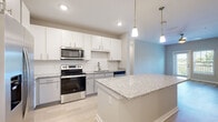 Located at 2101 Lakeview Rdg Cir in Apopka, Florida, this single-story home offers a clean, modern design with a bright and cohesive aesthetic throughout. The open-concept living and kitchen area serves as the heart of the home, featuring light hardwood-style flooring, recessed lighting, and a seamless flow between spaces. The kitchen is outfitted with white shaker cabinetry, speckled granite countertops, a subway tile backsplash, a central island with pendant lighting, and a full suite of stainless steel appliances including a side-by-side refrigerator with ice and water dispenser, electric range, built-in microwave, and dishwasher. The bedrooms offer ceiling fans and ample natural light through blinded windows; select rooms feature soft carpet flooring while others continue the light hardwood-style finish. The bathrooms are finished with white vanity cabinetry, granite countertops, and light tile flooring — one includes a tub-shower combination with grab bars, and another features a standalone shower with a large mirror. A dedicated laundry area houses a full-size Whirlpool washer and dryer with overhead shelving. Neutral gray walls and consistent finishes throughout create a cohesive, move-in-ready atmosphere.