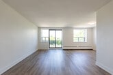 Located at 380 Gibb St in Oshawa, Ontario, this well-appointed one-bedroom, one-bathroom unit offers a thoughtfully designed layout with a clean, modern aesthetic throughout. Light-toned hardwood-style flooring runs continuously across the living areas, complementing the bright white walls and creating a fresh, cohesive feel.

The living room is generously sized and serves as the heart of the unit, featuring large windows and a sliding glass door that opens onto a private balcony with outdoor views of surrounding greenery. Baseboard heating units are positioned along the exterior walls, and ample natural light fills the space throughout the day.

The kitchen connects directly to the living area, offering a practical flow between spaces. It features white cabinetry, stainless steel appliances including a full-size refrigerator and dishwasher, and neutral countertops.

The bedroom is a comfortable size with its own window, hardwood-style flooring, and a full-width sliding closet, providing practical storage. An additional closet is also accessible nearby.

The bathroom is finished with classic white subway tile surrounding the bathtub and shower, large-format neutral floor tiles, and clean white fixtures, giving it a timeless and well-maintained appearance.