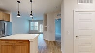 Located at 14000 Tapestry Dr in Orlando, Florida, this single-floor residence offers a thoughtfully designed layout that maximizes its compact footprint. The open-concept kitchen and living area serve as the heart of the home, where light wood-toned cabinetry, white quartz countertops, and a classic subway tile backsplash create a clean, contemporary aesthetic. A central kitchen island with pendant lighting provides additional prep space and a casual dining option, while a full suite of stainless steel appliances — including a refrigerator with ice maker, range, microwave, and dishwasher — ensures everyday functionality. Light wood-look flooring flows throughout the kitchen and living areas, adding warmth and continuity. The living room features soft carpeting, a ceiling fan, and a glass door that opens to an outdoor area, allowing natural light to fill the space. The generously sized primary bedroom is carpeted for comfort, outfitted with a ceiling fan, and benefits from natural light through a window with exterior views. It connects directly to a dedicated walk-in closet, offering practical storage. A separate bright nook with hardwood-style floors and dual windows provides a versatile space, ideal as a home office or reading area.