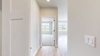 This 1,190-square-foot single-floor residence at 1211 Carrington Blvd in Mount Pleasant, Wisconsin offers a well-designed layout with 2 bedrooms, 2 bathrooms, 2 closets, and a dedicated utility room. The open-concept kitchen and living area serves as the heart of the home, featuring a large central island with a white quartz countertop and undermount sink, stainless steel appliances including a refrigerator, range, and microwave, white shaker-style upper cabinets, gray lower cabinets with matte black hardware, and pendant lighting. Light hardwood-style flooring flows throughout the main living areas, complementing the neutral color palette. The primary bedroom spans 210 square feet with plush carpet and a large window providing natural light and outdoor views. Its en-suite bathroom includes a glass-enclosed shower, white quartz vanity, and matte black fixtures, with direct access to a walk-in closet fitted with wire shelving. The second bedroom also features carpet flooring and a large window with exterior views. The second full bathroom offers a soaking tub, single vanity with quartz countertop, and matte black accents. Throughout, the home maintains a clean, modern aesthetic with neutral tones and consistent finishes.
