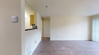 Located at 3788 NE 4th St, Unit F102 in Renton, WA, this 560-square-foot ground-floor apartment offers a functional and well-appointed single-level layout. The open living room is a standout space, featuring warm wood-look laminate flooring, a tile-surround fireplace as a central focal point, and a sliding glass door with vertical blinds that invites natural light and provides outdoor views. Track lighting and a ceiling fan add both style and utility to the living area. The galley-style kitchen is efficiently designed with light wood cabinetry, dark granite-style countertops, and a full suite of stainless steel appliances including an electric range, dishwasher, and refrigerator. A pass-through opening connects the kitchen to the living area, enhancing the open feel of the unit. The bathroom features wood-look flooring, a full soaking tub with a shower and curved curtain rod, matching light wood vanity cabinetry, and dark countertops consistent with the kitchen's design. Throughout the unit, neutral white walls and consistent flooring create a clean, cohesive aesthetic. The unit also includes a dedicated laundry area, adding everyday convenience to this compact and practical Renton residence.
