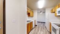 Located in Byron, MN, this single-floor, 2-bedroom, 2-bathroom residence offers a practical and comfortable layout with a clean, neutral aesthetic throughout. The kitchen is equipped with warm oak-toned cabinetry, white countertops, a built-in sink, a dishwasher, an electric range, and an over-the-range microwave — providing ample storage and functionality. Hardwood-style flooring runs through the kitchen and connecting hallways, lending a cohesive look to the common areas. The spacious living area features plush carpeting, a ceiling fan, and transitions seamlessly to an adjacent space, offering flexibility for various furniture arrangements. The primary bedroom is generously sized, featuring carpet flooring, a large sliding glass door with vertical blinds that opens to an outdoor area with natural views, baseboard heating, and a wall-unit air conditioner. The second bedroom also features carpet, a natural light-filled window with wooded views, baseboard heating, and a sliding closet with raised-panel doors. Both bathrooms are functional and well-appointed; one includes a walk-in shower stall alongside open wooden shelving. Tile flooring in the bathrooms and hallways adds a practical touch. Two hallways connect the rooms efficiently, and the overall layout ensures privacy and ease of movement throughout the residence.