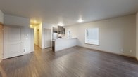 This well-appointed third-floor unit at 3410 Orlando St in Port Orchard, Washington offers a thoughtfully designed single-level layout with modern finishes throughout. The open-concept living and kitchen area serves as the heart of the space, featuring rich dark hardwood-style flooring, neutral-toned walls, and abundant natural light from large windows fitted with blinds. A sliding glass door leads to a private balcony, providing outdoor views of the surrounding landscape.

The kitchen is equipped with stainless steel appliances — including a refrigerator, electric range, and over-the-range microwave — complemented by dark wood cabinetry with sleek hardware and a light-toned peninsula countertop that doubles as a breakfast bar. The open sightlines between the kitchen and living area create a spacious, airy feel.

The bedrooms are carpeted for comfort, with generous windows allowing natural light to fill each room. The primary bedroom features sliding closet doors and direct balcony access. Additional bedrooms offer ample space and window views.

Two full bathrooms serve the unit, each finished with wood-tone vanity cabinetry, white countertops, tub-shower combinations, and durable wood-style flooring. The overall design is clean, contemporary, and move-in ready.