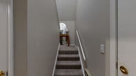 Located at 11001 W 133rd Ter in Overland Park, KS, this two-story, 2-bedroom, 3-bathroom home offers a thoughtfully designed layout across two levels. The main living floor hosts the primary spaces, beginning with a combined kitchen and living area. The kitchen features light maple cabinetry, granite-style countertops, a peninsula with a double sink, and stainless steel appliances including a refrigerator, range, and microwave. The adjoining living room impresses with vaulted ceilings, a classic white-mantled fireplace, and natural light streaming through curtained windows. The bedrooms are carpeted and serene, with ceiling fans and ample natural light. The spacious primary bedroom includes a generous walk-in closet with wire shelving. All three bathrooms are finished with wood-look tile flooring, light maple vanities, and granite-style countertops; one features a soaking tub and another a glass-enclosed shower. A staircase connects the main living floor to the lower level, where an attached single-car garage with an automatic opener provides convenient access. Neutral warm-gray tones throughout create a cohesive and welcoming ambiance.