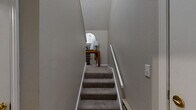 Located at 11001 W 133rd Ter in Overland Park, KS, this two-story, 2-bedroom, 3-bathroom home offers a thoughtfully designed layout across two levels. The main living floor hosts the primary spaces, beginning with a combined kitchen and living area. The kitchen features light maple cabinetry, granite-style countertops, a peninsula with a double sink, and stainless steel appliances including a refrigerator, range, and microwave. The adjoining living room impresses with vaulted ceilings, a classic white-mantled fireplace, and natural light streaming through curtained windows. The bedrooms are carpeted and serene, with ceiling fans and ample natural light. The spacious primary bedroom includes a generous walk-in closet with wire shelving. All three bathrooms are finished with wood-look tile flooring, light maple vanities, and granite-style countertops; one features a soaking tub and another a glass-enclosed shower. A staircase connects the main living floor to the lower level, where an attached single-car garage with an automatic opener provides convenient access. Neutral warm-gray tones throughout create a cohesive and welcoming ambiance.