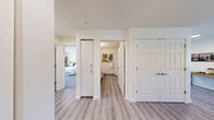 Located at 4800 B St in Springfield, Oregon, this well-appointed one-bedroom, two-bathroom residence offers a thoughtfully designed single-floor layout. The open-concept kitchen and living area serves as the heart of the home, where light wood-look flooring flows throughout. The kitchen is equipped with white cabinetry, granite-style countertops, black appliances including a refrigerator, range, and dishwasher, and ample storage reaching to the ceiling. The combined living and dining area is bright and welcoming, featuring a large window that brings in natural light and views of surrounding greenery. A dedicated office provides carpeted flooring, a window with outdoor views, and a quiet space ideal for working from home. The spacious primary bedroom features plush carpeting, generous natural light from a large window, and a comfortable, relaxing ambiance. Two full bathrooms are finished with wood-look flooring, granite-topped vanities with white cabinetry, and walk-in shower stalls. A hallway connects the rooms efficiently, and an entryway with additional cabinetry and granite countertop offers practical storage. The overall aesthetic is clean and modern with neutral tones throughout.