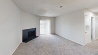 Located at 6421 S 33rd W Ave in Tulsa, Oklahoma, this single-story, 3-bedroom, 2-bathroom home offers a practical and comfortable layout across a well-utilized floor plan. The living room serves as the heart of the home, anchored by a sleek black tile fireplace and a sliding glass door with vertical blinds that fills the space with natural light and provides outdoor access. Soft carpeting runs throughout the living and bedroom areas, creating a warm, cohesive feel. The kitchen is a functional galley-style space featuring two-tone cabinetry — white uppers and grey lowers — white subway tile backsplash, white countertops, stainless steel appliances including a refrigerator, over-the-range microwave, and electric range, plus durable hardwood-style flooring. A ceiling fan enhances airflow into the adjacent dining area. The primary bedroom is a generous size and includes a walk-in closet outfitted with built-in shelving and hanging rods. The additional bedrooms are well-proportioned with carpet flooring and natural light from windows. Both bathrooms feature clean, white tub/shower combos. A dedicated laundry room with washer hookups, a utility shelf, and hardwood-style flooring adds everyday convenience. Textured ceilings are present throughout the home.