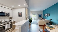 Located at 3000 Valley Forge Circle in King of Prussia, PA, this well-appointed 2-bedroom, 2-bathroom residence offers a thoughtfully designed single-floor layout that balances comfort and modern style. The open kitchen is a standout feature, showcasing two-tone cabinetry with high-gloss white upper cabinets and warm wood-grain lower cabinets, sleek white quartz countertops, a textured tile backsplash, and a full suite of stainless steel appliances. Light hardwood flooring ties the kitchen and living area together seamlessly. The living room provides a relaxed, airy atmosphere with neutral tones and light-colored flooring. The generously sized primary bedroom features soft carpet, a soothing accent wall, and direct access to a private balcony overlooking the surrounding greenery and open skies. The second bedroom doubles as a flexible office space with a bold terracotta accent wall and closet storage. Two bathrooms serve the residence — one featuring a sleek glass-enclosed walk-in shower with large-format tile, and the other a full bath with a clean white vanity. The balcony offers an elevated outdoor retreat with open views of the landscaped surroundings and tree-lined horizon.