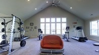 Located at 5315 Avery Road in Dublin, Ohio, this fitness center offers a welcoming and functional environment for exercise and wellness. The space is defined by its impressive vaulted ceiling, which rises dramatically overhead and is complemented by a large ceiling fan that ensures comfortable air circulation throughout workouts. Recessed lighting is evenly distributed across the ceiling, providing consistent illumination throughout the space.

A striking bank of tall, multi-pane windows dominates one wall, flooding the interior with natural light and offering views of the surrounding outdoor environment. The bright, airy ambiance created by this generous fenestration makes the space feel open and energizing.

The fitness area is equipped with a range of cardio machines, including treadmills, an elliptical trainer, and a stationary bike, all thoughtfully arranged to allow ample room for movement. A cushioned seating piece provides a comfortable spot to rest between sets. Framed artwork and motivational décor adorn the walls, adding a personalized touch to the environment. Soft, patterned carpeting covers the floor, contributing to the overall comfort of the space. The single-floor layout ensures easy accessibility, making this a practical and inviting fitness destination.