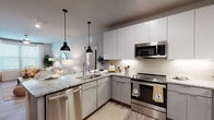 This well-appointed single-story residence at 8801 Hidden River Pkwy in Tampa, Florida offers a thoughtfully designed open-concept layout with modern finishes throughout. The kitchen is a standout feature, showcasing granite countertops, a large island with seating for multiple guests, crisp white upper cabinetry, sleek lower cabinets, a subway tile backsplash, and a full suite of stainless steel appliances. Stylish pendant lighting illuminates the island, creating a warm and functional cooking and dining space that flows seamlessly into the living area. The living room is bright and inviting, highlighted by large windows that allow abundant natural light, light wood-style flooring, and a ceiling fan overhead. The multiple bedrooms are carpeted for comfort and each features generous windows with blinds and sheer curtains, ceiling fans, and ample space. The bathrooms continue the home's refined aesthetic with granite-topped vanities, light wood-style tile flooring, and a tub-shower combination. Neutral tones and contemporary design choices are carried throughout, creating a cohesive and comfortable atmosphere well-suited to everyday living in the heart of Tampa.