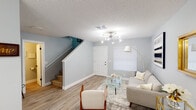 This well-appointed two-story home offers a thoughtfully designed layout that balances comfort and modern style. The main floor welcomes you through a front entry that opens into a bright living area, featuring light wood-look flooring, soft gray walls, and a contemporary sputnik-style chandelier. The living room provides ample space for seating and flows seamlessly into the dining area, which is anchored by a round marble-top table beneath a matching chandelier. Natural light filters in through slatted blinds, enhancing the airy atmosphere throughout.

The kitchen is positioned adjacent to the dining area and features white cabinetry, dark countertops, a tile backsplash, stainless steel appliances, and a pass-through counter that maintains visual connectivity with the living and dining spaces. A staircase with carpeted treads leads to the upper floor, where multiple bedrooms are located. Each bedroom is finished with warm neutral tones, wood-look flooring, and windows with blinds for natural light and privacy.

The bathrooms include a full bath with a shower-tub combination, white vanity, and clean gray walls, as well as a secondary bath with a single vanity and mirror. Consistent use of light tones, gold accents, and modern fixtures throughout the home creates a cohesive and inviting aesthetic.