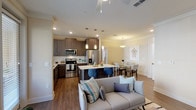 This well-designed 2-bedroom, 2-bathroom residence spans a single floor and offers a generous, thoughtfully laid-out living environment. The open-concept main area seamlessly connects the kitchen, dining, and living spaces, creating an inviting flow throughout. The kitchen features dark wood cabinetry, light quartz countertops, stainless steel appliances including a refrigerator with ice maker, microwave, and range, as well as a central island with pendant lighting and seating. Large windows throughout the living area allow abundant natural light and outdoor views, while ceiling fans provide year-round comfort. Hardwood-style flooring runs throughout the main living spaces and bedrooms, adding warmth and continuity. The primary bedroom is generously sized with a walk-in closet offering wire shelving on both sides, and an en-suite bathroom featuring a glass-enclosed shower, granite countertop vanity, and large-format tile flooring. The second bedroom is well-proportioned with its own natural light and closet access. The second bathroom includes a soaking tub with tiled surround and a matching dark wood vanity with granite countertop. A dedicated in-unit laundry room with a full-size washer and dryer and overhead shelving completes this functional and stylish residence.