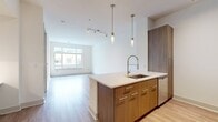 This contemporary 640 square foot apartment offers a thoughtful blend of comfort and functionality. The single-floor layout maximizes space efficiency, featuring one bedroom and one bathroom. The heart of the home is an open-concept kitchen and living area, boasting sleek wooden cabinetry, stainless steel appliances, and a practical island with a built-in sink. 

The kitchen flows seamlessly into the living space, which is illuminated by large windows that invite natural light and offer urban views. Hardwood flooring extends throughout the main living areas, enhancing the modern aesthetic. The bedroom, measuring 160 square feet, provides ample space and includes plush carpeting for added comfort. 

A standout feature is the in-unit laundry, concealed behind elegant white doors, offering convenience and privacy. The bathroom showcases a clean, minimalist design with a spacious vanity and a glass-enclosed shower. 

High ceilings and neutral color palettes throughout create an airy, expansive feel. The apartment's thoughtful design maximizes storage with built-in closets and shelving. Located at 322 N Broad, unit 1642, this apartment combines style, functionality, and urban living in one compact yet comfortable space.