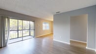 Located at 803 Don Quixote Ave in Orlando, FL, this single-floor, one-bedroom, one-bathroom residence offers a practical and comfortable layout with modern finishes throughout. The open living area is a standout feature, characterized by light gray laminate flooring, neutral-toned walls, and a textured ceiling. Large sliding glass doors flood the space with natural light and open to a private balcony with outdoor views of surrounding greenery, creating a seamless indoor-outdoor connection. A secondary window further enhances the bright, airy atmosphere of the living area. The kitchen is equipped with white cabinetry, granite-look countertops, a double stainless steel sink, and a full electric range with overhead ventilation. The bedroom is a comfortable, well-proportioned retreat featuring plush carpeting, soft blue-gray walls, a large window with natural light, and direct access to a dedicated closet with louvered doors. The full bathroom is clean and functional, outfitted with a tub-shower combination, white tile surround, a granite-top vanity with white cabinetry, and wood-look tile flooring. A hallway and entrance area complete the efficient floor plan, making this a well-organized and inviting space in the heart of Orlando.