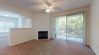 This single-floor residence offers a well-organized layout with a variety of functional living spaces. The living room is a comfortable, carpeted area highlighted by a corner fireplace with a tile surround, crown molding, a ceiling fan with light fixture, and a sliding glass door that opens to a balcony or patio, framing views of lush surrounding greenery. An arched passageway connects the living area to additional rooms, adding an architectural detail to the open feel.

The kitchen is notably updated, featuring white cabinetry, granite-style countertops, a subway tile backsplash, and wood-look flooring. Stainless steel appliances — including a refrigerator, range, microwave, and dishwasher — are complemented by track lighting overhead and a window that draws in natural light.

The bedrooms are carpeted and bright, each with ceiling fans and windows fitted with blinds. Several rooms include walk-in or reach-in closets for ample storage. The primary bathroom features a long, white vanity with an extended mirror, wood-look flooring, and direct access to the bedroom. A secondary bathroom offers a tub-shower combination with sliding glass doors and matching flooring, maintaining a clean, cohesive aesthetic throughout.