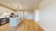 This single-story, 1,440-square-foot residence at 930 Terrapin Ln, Unit 102, features 3 bedrooms, 2 bathrooms, and 2 closets, delivering a clean, modern aesthetic with high-quality finishes. The open-concept kitchen and living area serves as the heart of the home, showcasing light hardwood-style flooring, white shaker cabinetry, stainless steel appliances, a central island with pendant lighting, and recessed ceiling lights. The living room extends naturally from the kitchen and offers exterior door access with natural light. The spacious primary bedroom spans 370 square feet, complete with plush carpet, a ceiling fan, a stylish barn door, and direct access to an en suite bathroom featuring gray shaker vanity cabinetry, white countertops, matte black hardware, a glass-enclosed walk-in shower, and hardwood-style flooring. The secondary bathroom mirrors this modern design with a full tub-shower combo and matching fixtures. Additional bedrooms are carpeted, include ceiling fans, and receive ample natural light through windows with outdoor views. Generous closet space is provided with wire shelving systems. The attached garage features a concrete floor, automatic opener, and interior access door, completing this well-appointed home.